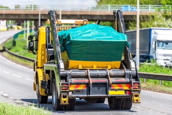 Skip hire lorry delivering a covered skip for waste collection in Leeds